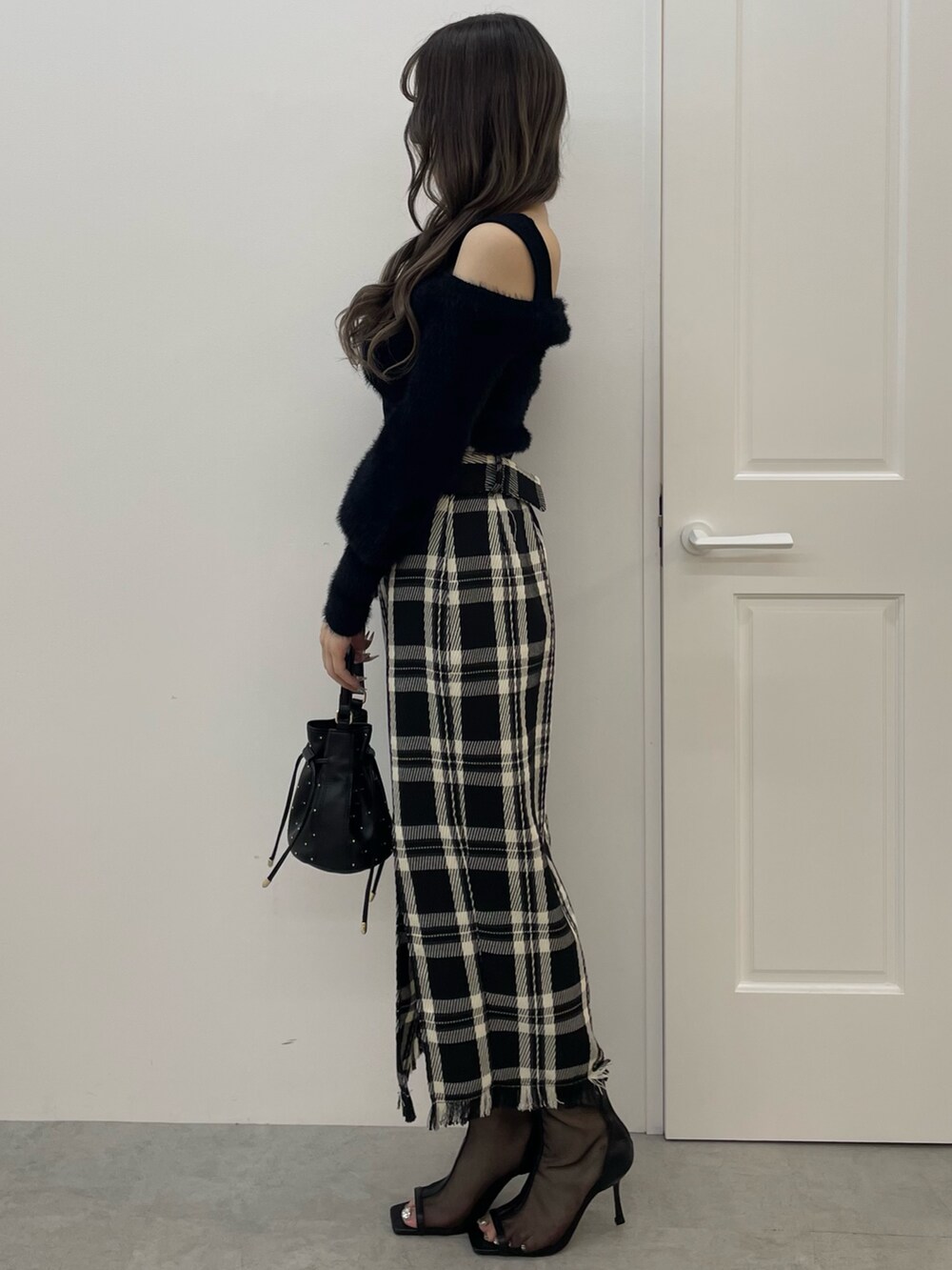 ブラック系のニット/セーター、ブラック系のスカート、ブラック系のハンドバッグを着用したレディースの夏コーディネートの3枚目の写真