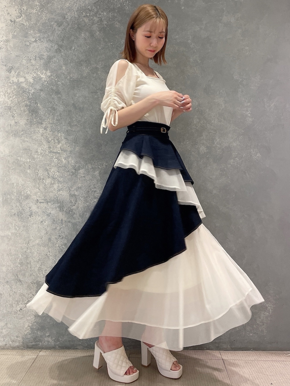 ホワイト系のTシャツ/カットソー、ブルー系のデニムスカート、ホワイト系のサンダルを着用したレディースの夏コーディネートの7枚目の写真