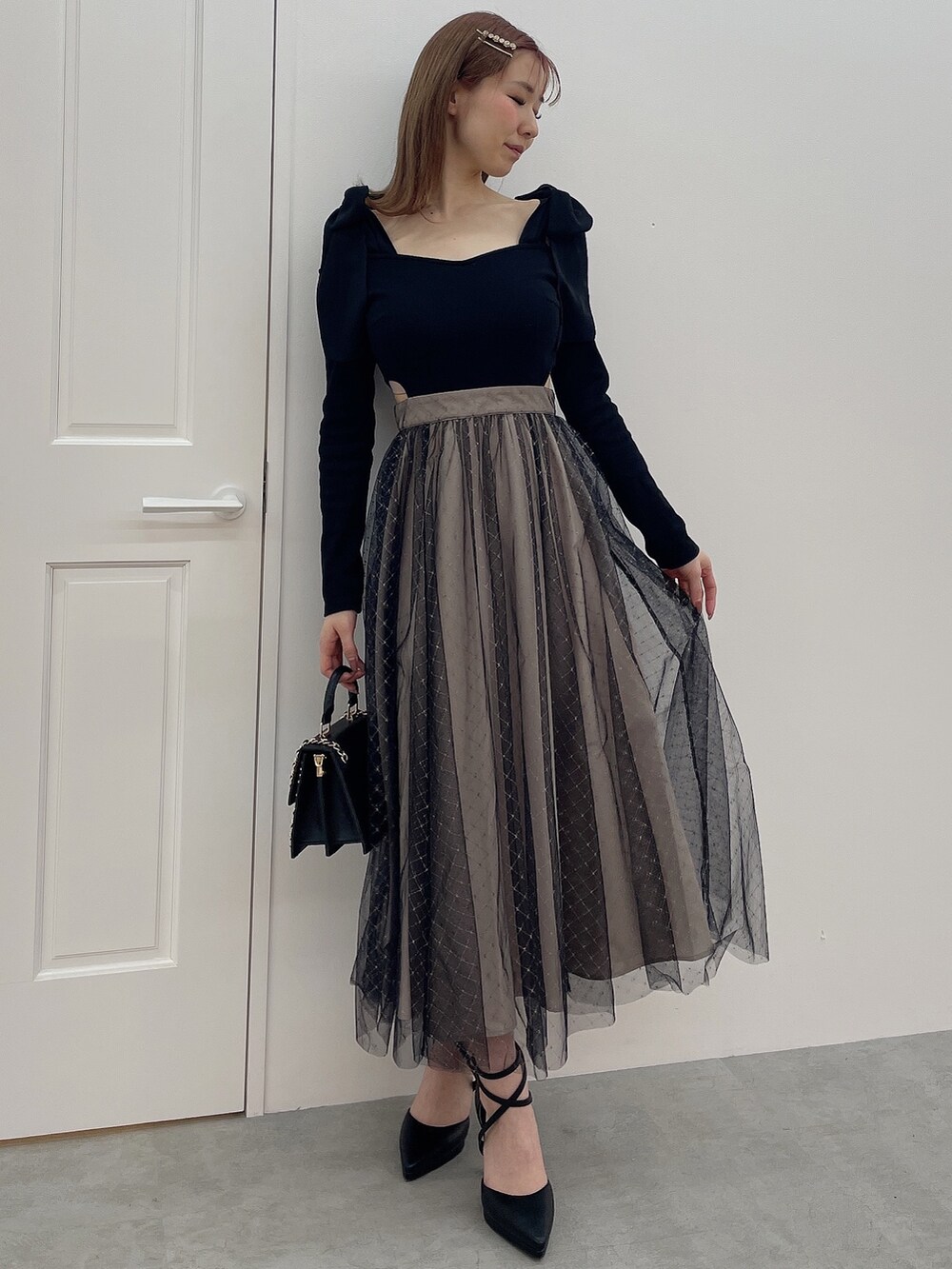 ブラック系のワンピース、ブラック系のハンドバッグ、ブラック系のパンプスを着用したレディースの冬コーディネートの2枚目の写真