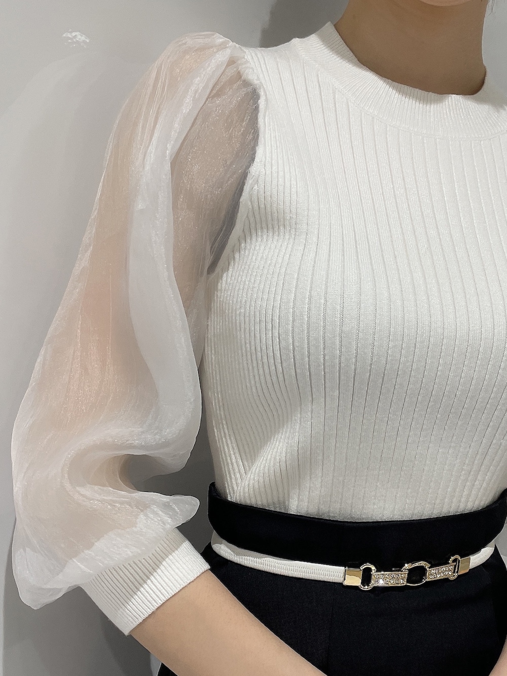 ホワイト系のニット/セーター、ブラック系のスカート、ブラック系のパンプスを着用したレディースの春コーディネートの4枚目の写真