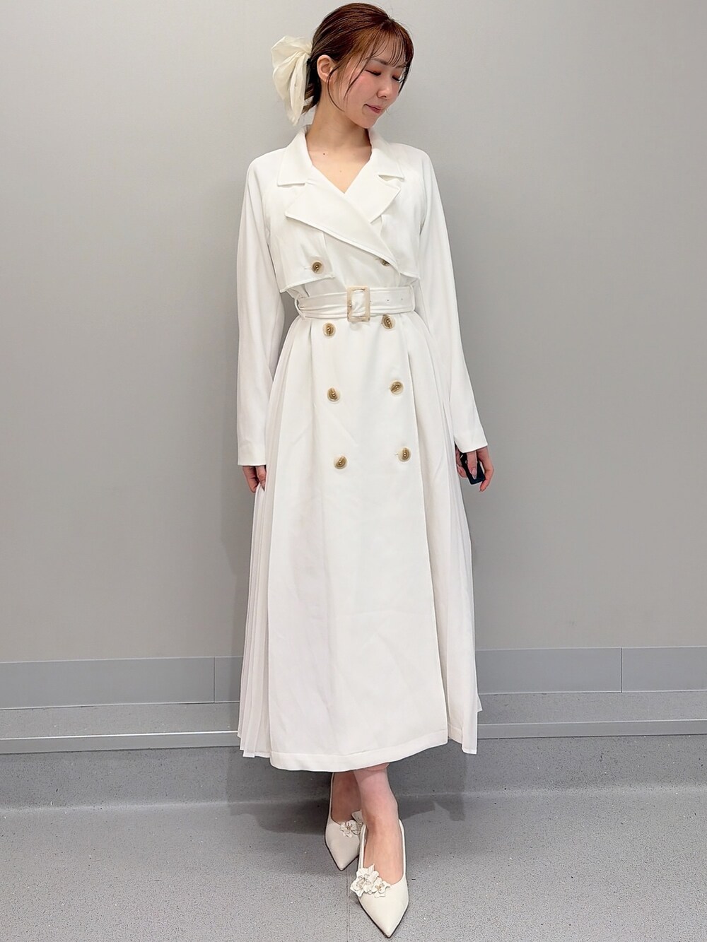 ホワイト系のトレンチコート、ピンク系のショルダーバッグ、オレンジ系のワンピースを着用したレディースの冬コーディネートの3枚目の写真