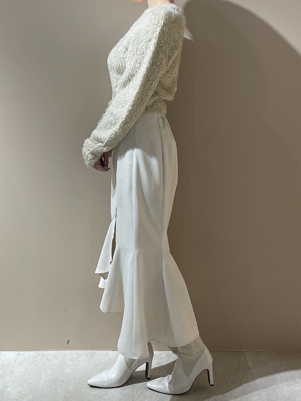 ベージュ系のニット/セーター、ホワイト系のスカート、ホワイト系のブーツを着用したレディースの秋コーディネートの2枚目の写真