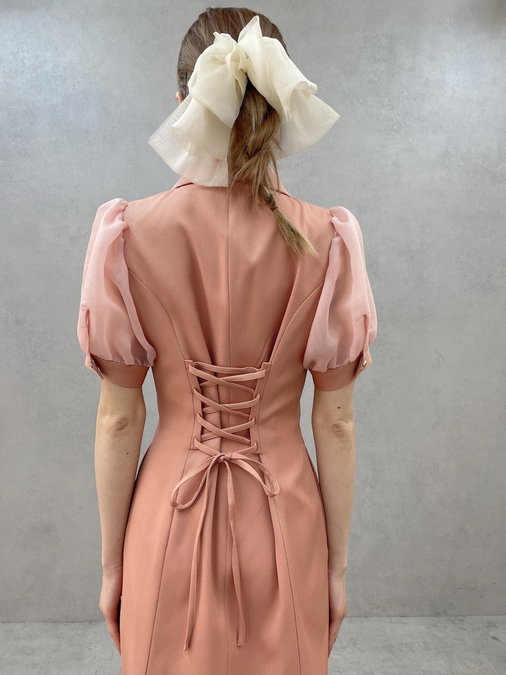 オレンジ系のワンピース、ホワイト系のブーツ、ホワイト系のバレッタ/ヘアクリップを着用したレディースの春コーディネートの6枚目の写真