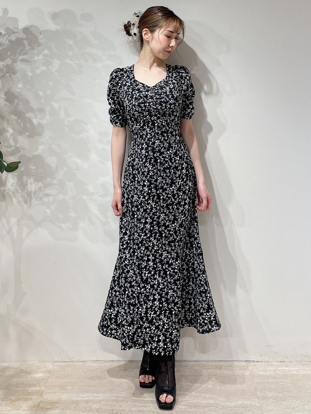 ブラック系のワンピース、ブラック系のブーツ、ベージュ系のシュシュを着用したレディースの春コーディネートの2枚目の写真