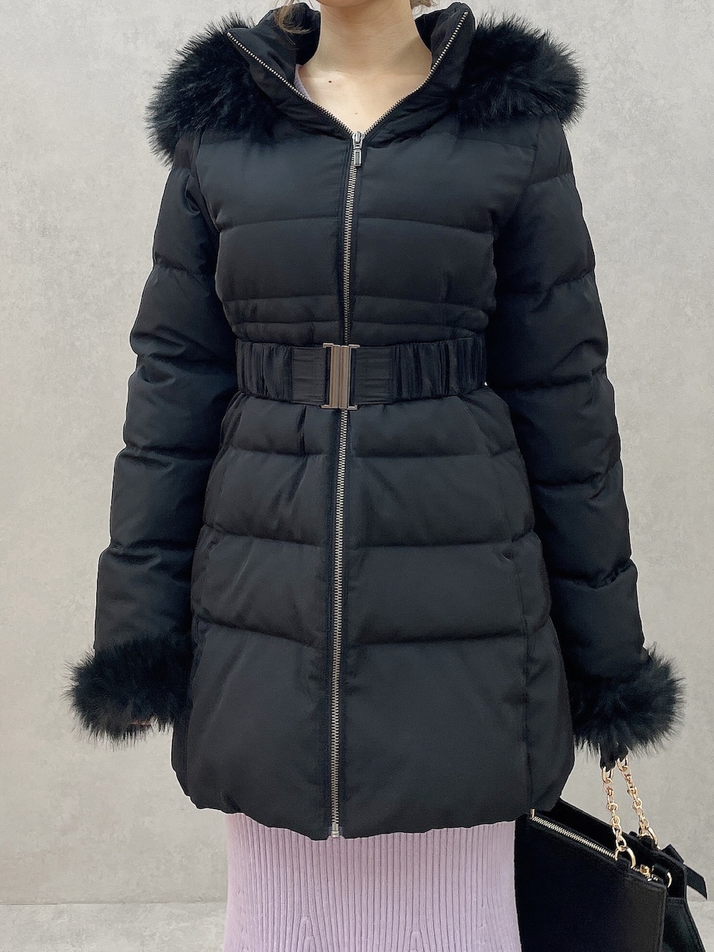 ブラック系のダウンジャケット/コート、パープル系のワンピース、ブラック系のハンドバッグを着用したレディースの秋コーディネートの6枚目の写真