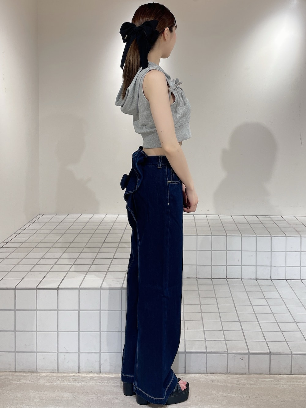 グレー系のパーカー、ブルー系のデニムパンツ、ブラック系のサンダルを着用したレディースの春コーディネートの2枚目の写真