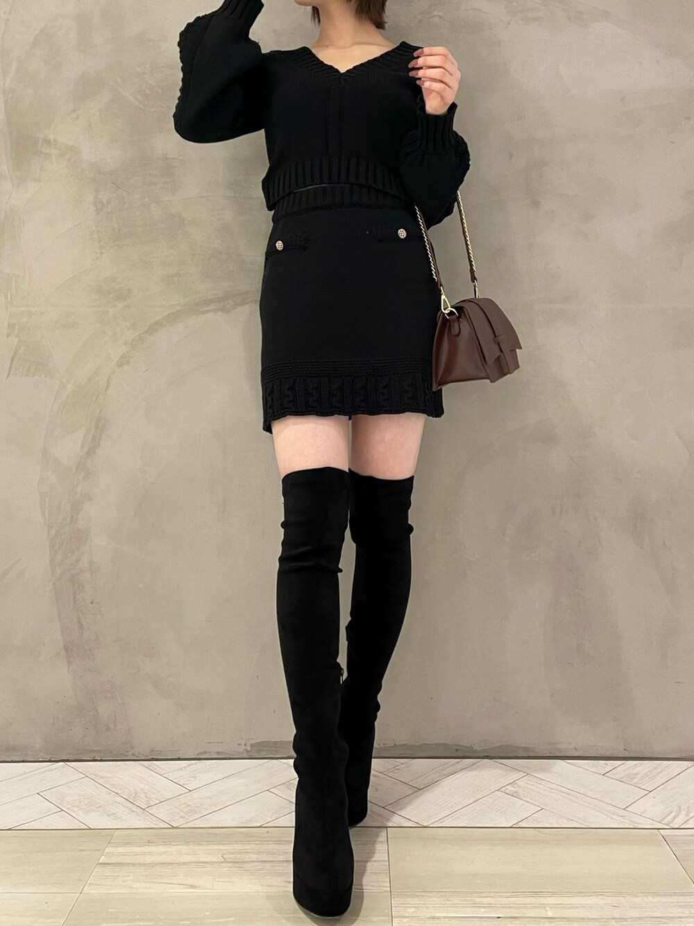 ブラウン系のハンドバッグ、ブラック系のブーツ、ブラック系のニット/セーターを着用したレディースの秋コーディネートの2枚目の写真