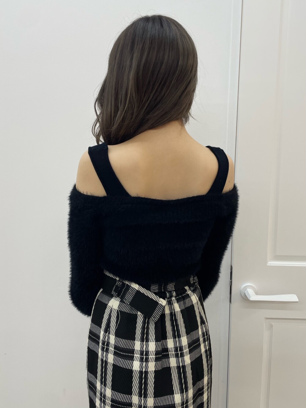 ブラック系のニット/セーター、ブラック系のスカート、ブラック系のハンドバッグを着用したレディースの夏コーディネートの6枚目の写真