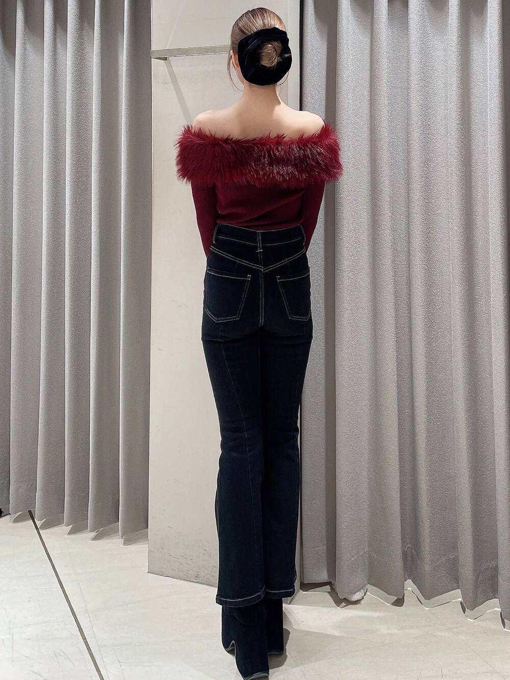 レッド系のニット/セーター、ブラック系のデニムパンツ、ブラック系のブーツを着用したレディースの秋コーディネートの3枚目の写真