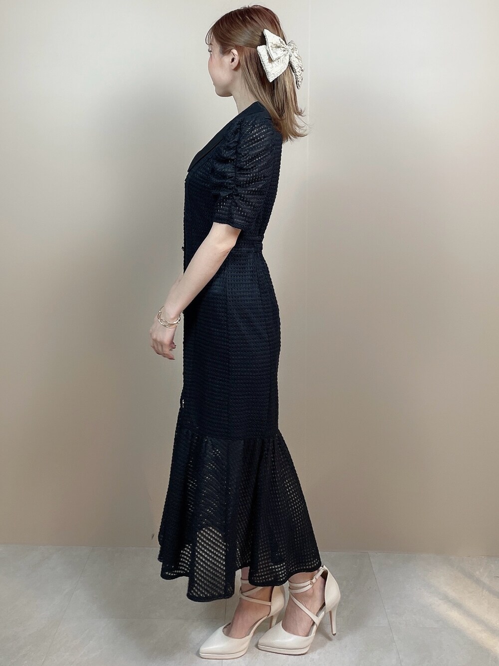ブラック系のワンピース、ホワイト系のパンプス、ベージュ系のバレッタ/ヘアクリップを着用したレディースの冬コーディネートの2枚目の写真