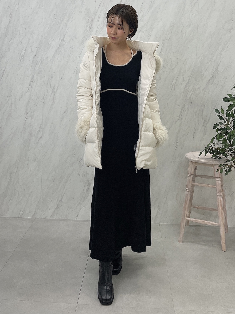 ブラック系のブーツ、ブラック系のワンピース、ホワイト系のダウンジャケット/コートを着用したレディースの夏コーディネートの4枚目の写真