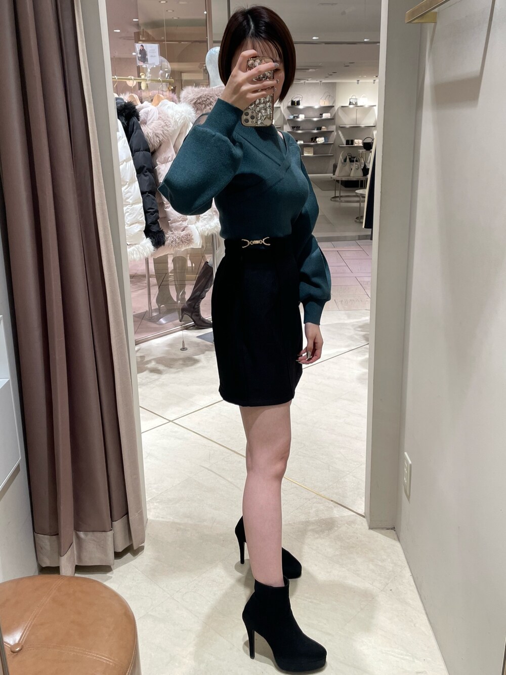 グリーン系のニット/セーター、ブラック系のスカート、ブラック系のブーツを着用したレディースの冬コーディネートの3枚目の写真