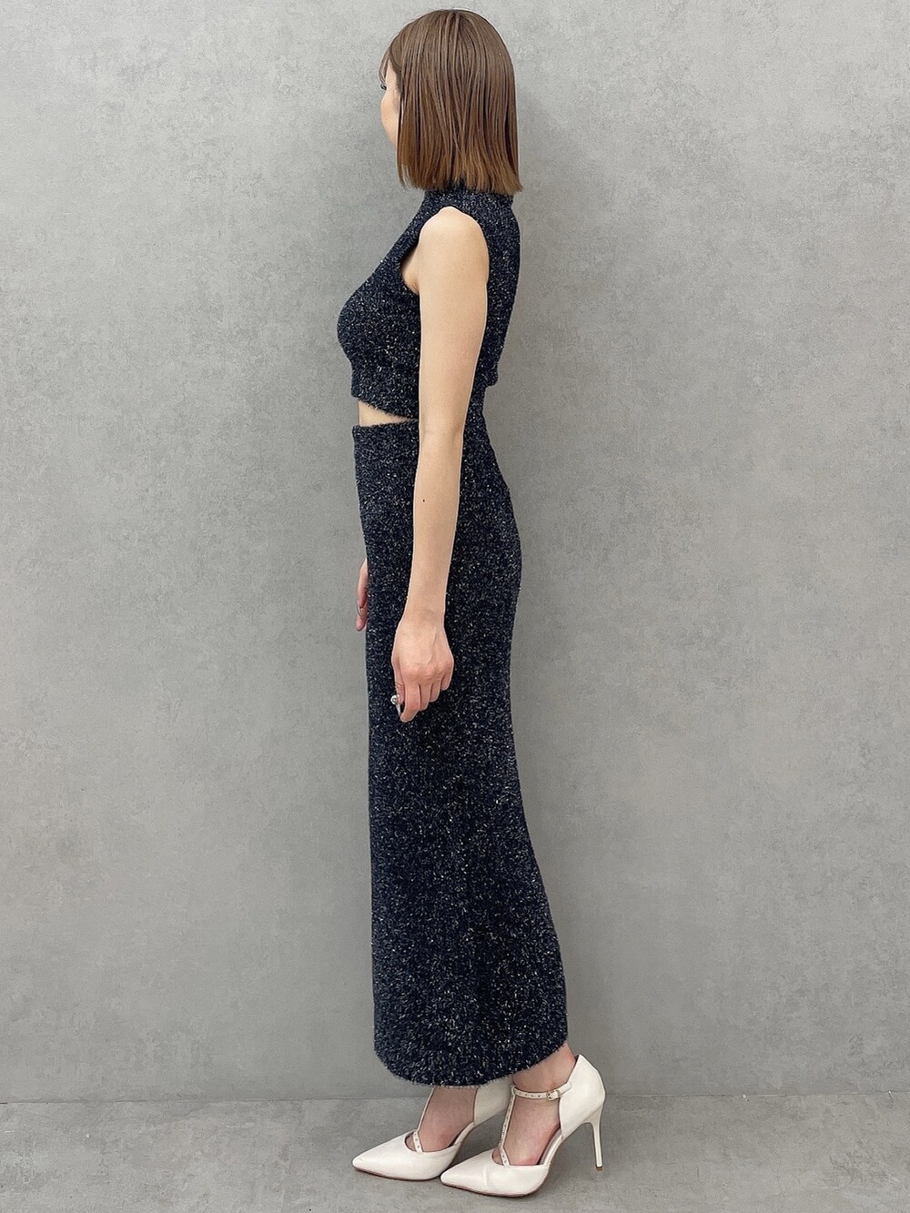 ブラック系のニット/セーター、ブラック系のスカート、ホワイト系のパンプスを着用したレディースの夏コーディネートの3枚目の写真