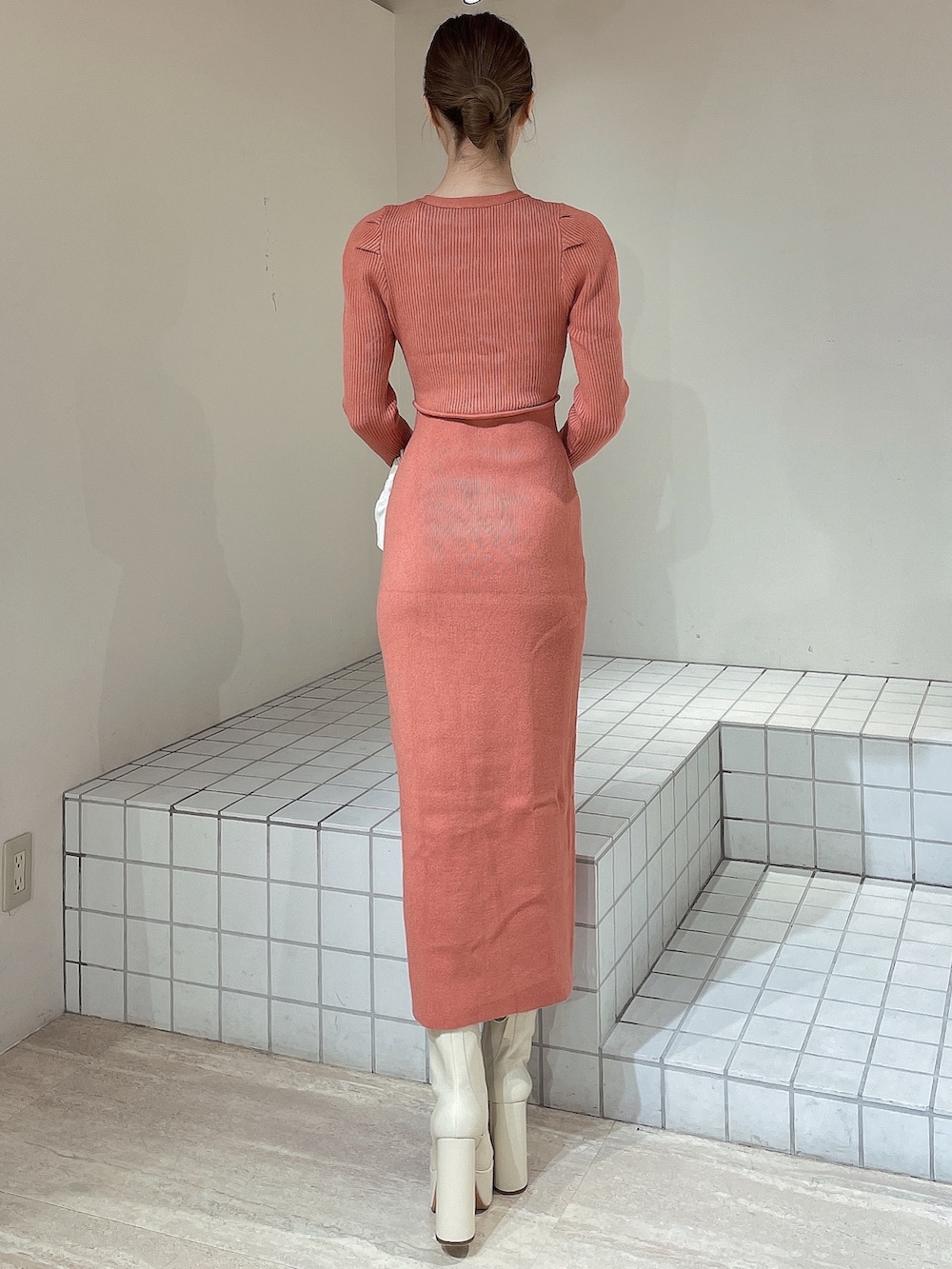 オレンジ系のワンピース、ホワイト系のハンドバッグ、ホワイト系のブーツを着用したレディースの冬コーディネートの3枚目の写真