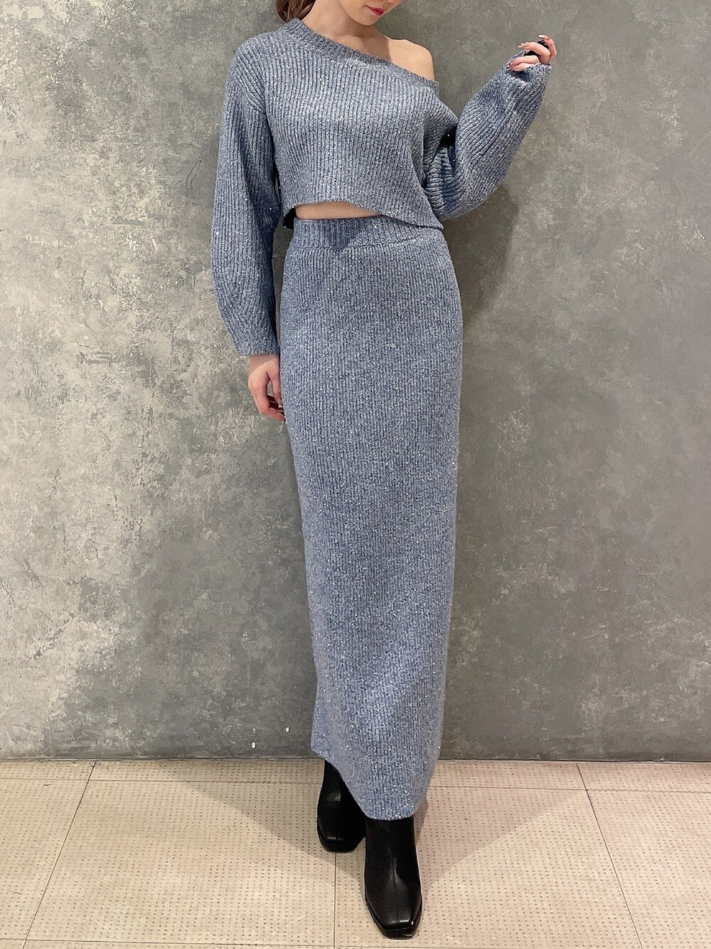 ブルー系のニット/セーター、ブルー系のスカート、ブラック系のブーツを着用したレディースの秋コーディネートの2枚目の写真