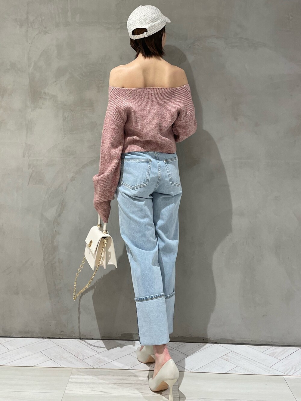 ピンク系のニット/セーター、ホワイト系のハンドバッグ、ブルー系のデニムパンツを着用したレディースの冬コーディネートの4枚目の写真