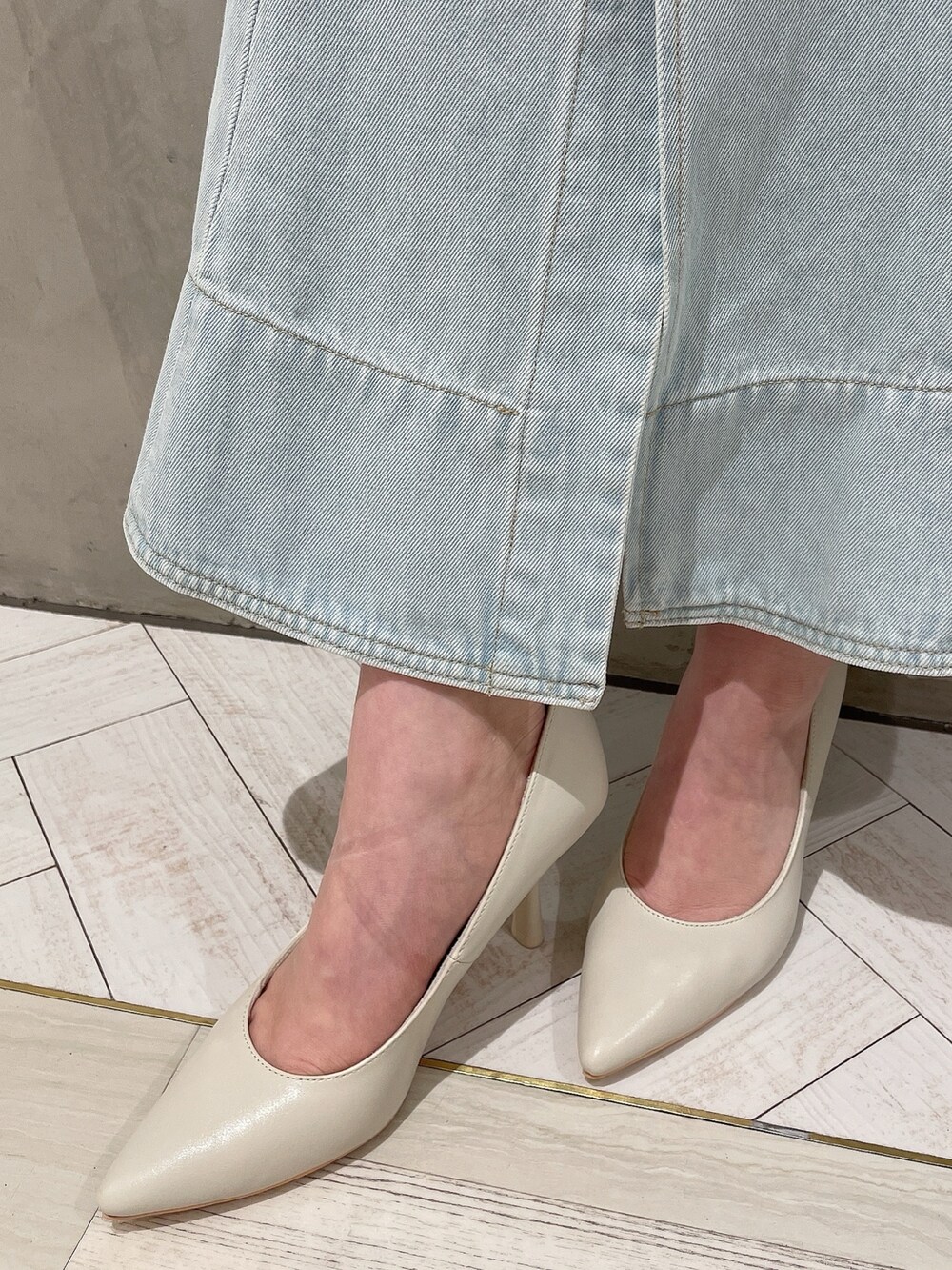 ホワイト系のハンドバッグ、ホワイト系のパンプス、ブルー系のデニムスカートを着用したレディースの冬コーディネートの10枚目の写真