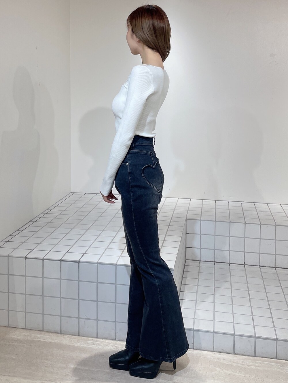 グレー系のカーディガン/ボレロ、ホワイト系のニット/セーター、ブラック系のデニムパンツを着用したレディースの冬コーディネートの6枚目の写真