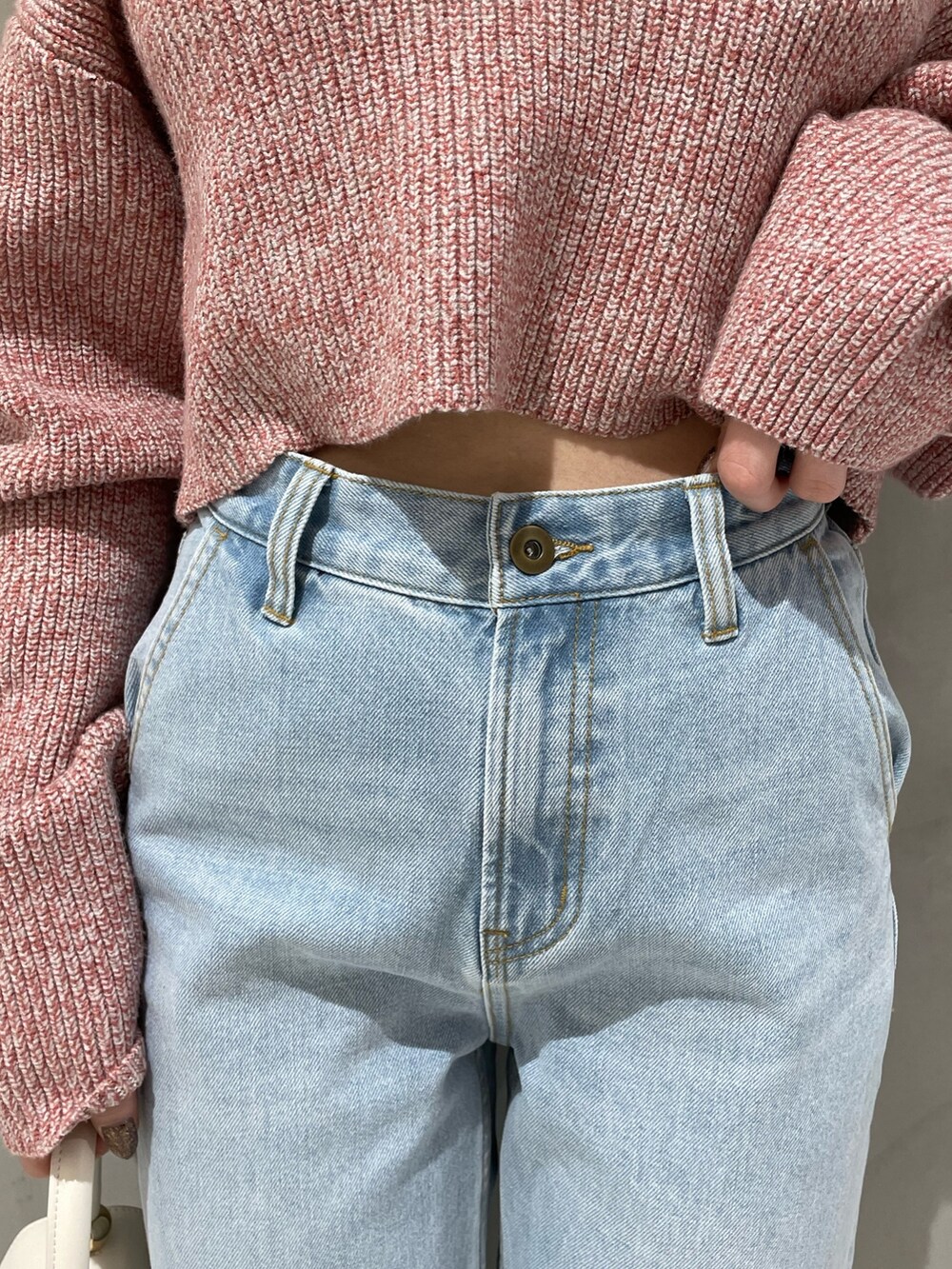 ピンク系のニット/セーター、ホワイト系のハンドバッグ、ブルー系のデニムパンツを着用したレディースの冬コーディネートの6枚目の写真