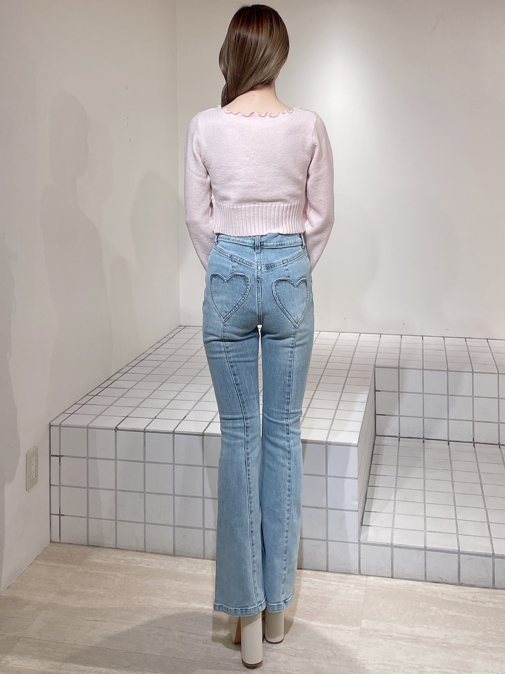 ピンク系のニット/セーター、ブルー系のデニムパンツ、ホワイト系のブーツを着用したレディースの冬コーディネートの4枚目の写真