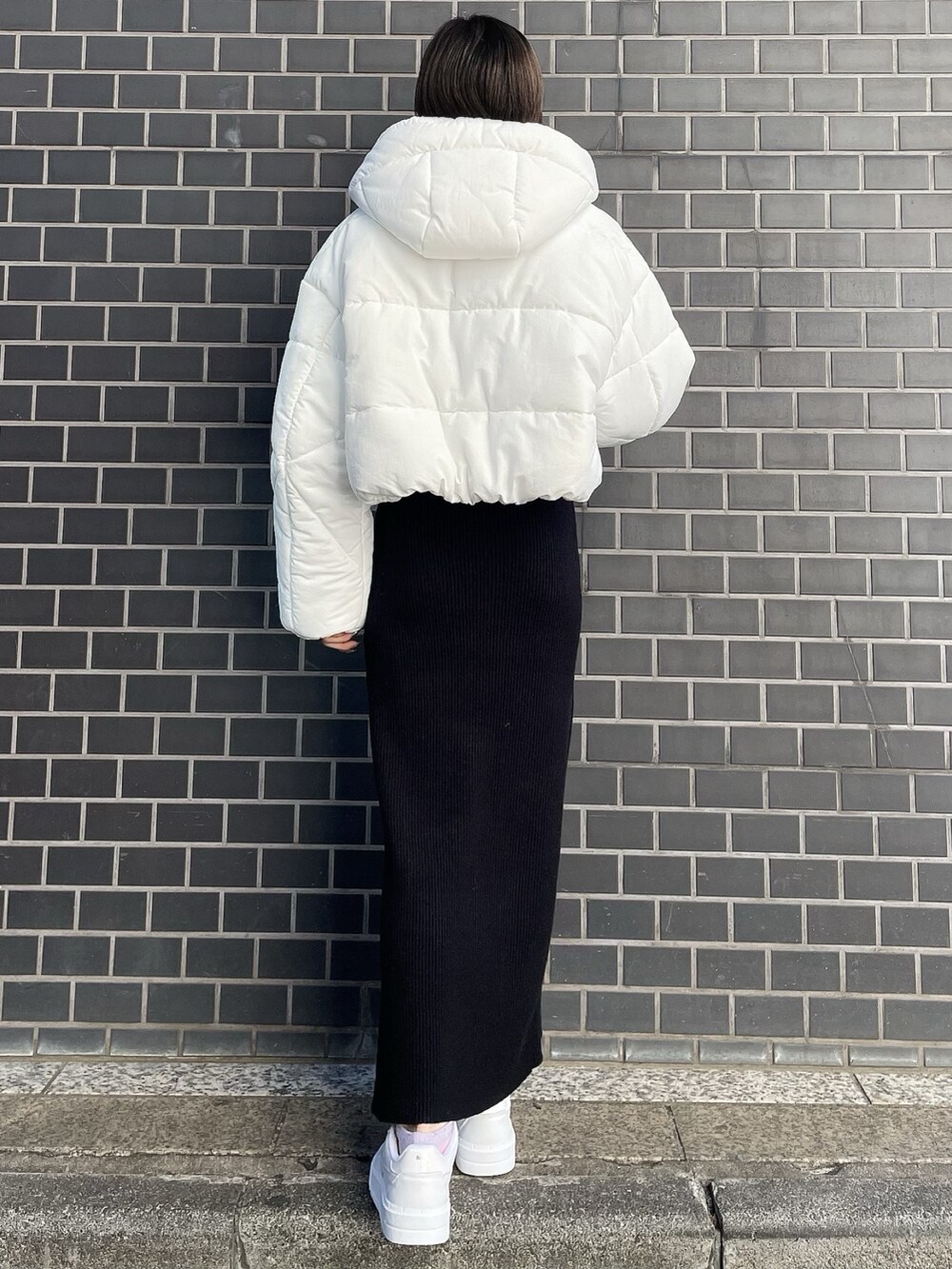 ブラック系のワンピース、ホワイト系のブルゾン、ホワイト系のスニーカーを着用したレディースの冬コーディネートの4枚目の写真