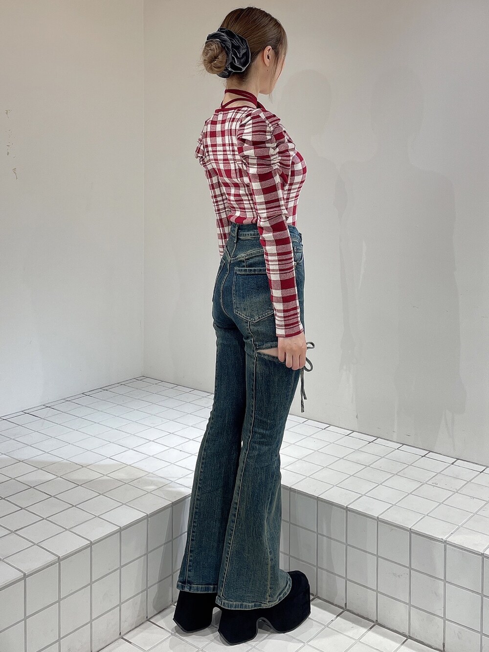 レッド系のニット/セーター、ブルー系のデニムパンツ、ブラック系のブーツを着用したレディースの秋コーディネートの3枚目の写真