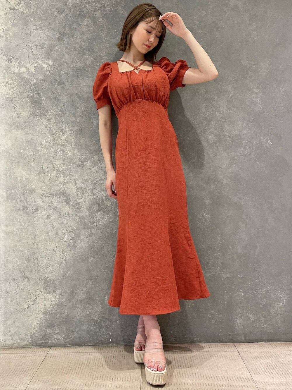 オレンジ系のワンピース、ホワイト系のサンダルを着用したレディースの春コーディネートの3枚目の写真