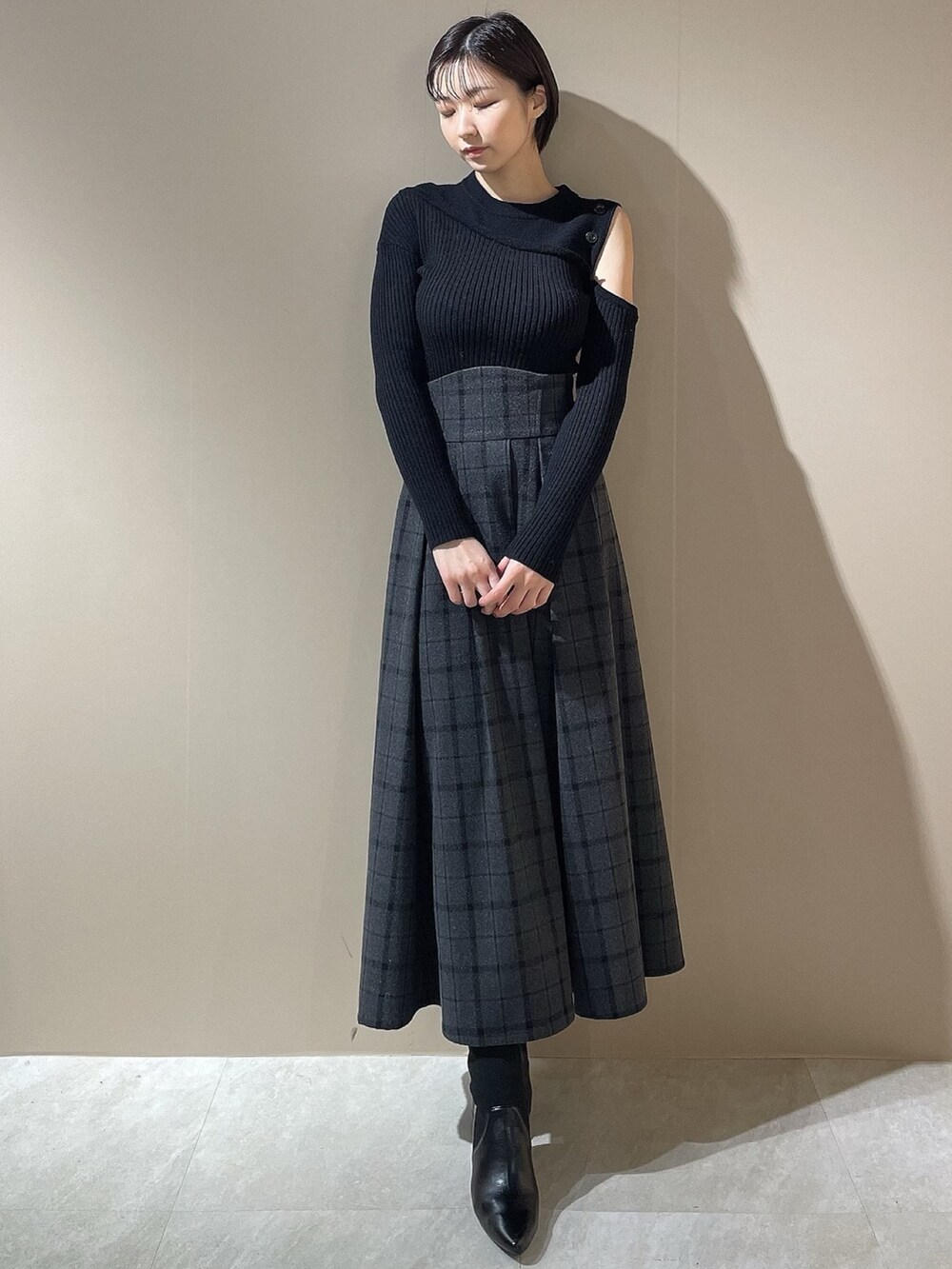 ブラック系のニット/セーター、ブラック系のスカート、ブラック系のブーツを着用したレディースの秋コーディネートの2枚目の写真