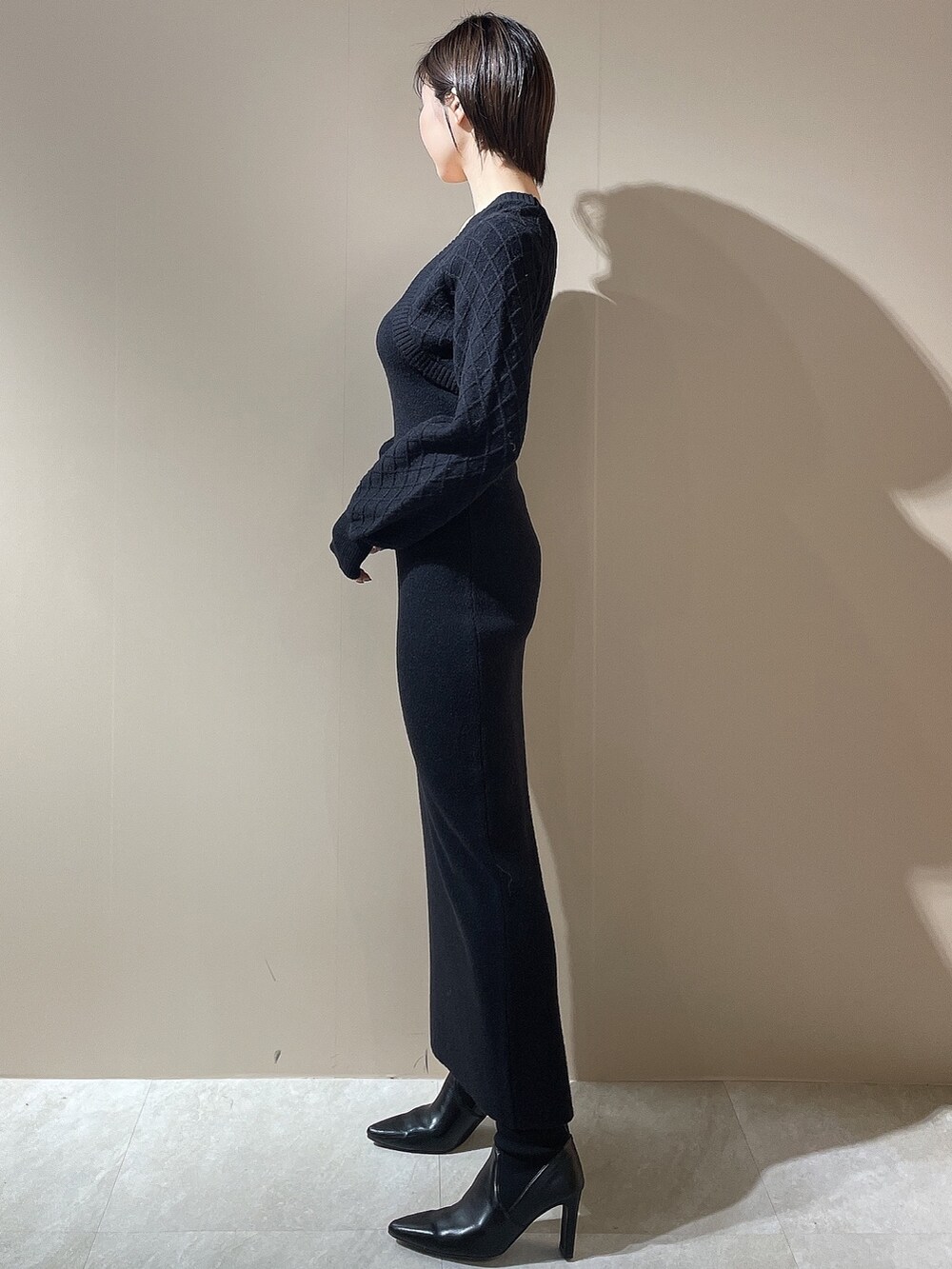 ブラック系のダウンジャケット/コート、ブラック系のワンピース、ブラック系のブーツを着用したレディースの秋コーディネートの6枚目の写真