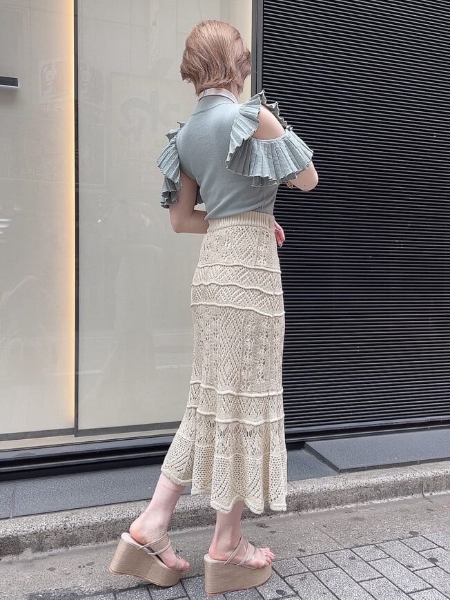 ベージュ系のスカート、ホワイト系のサンダル、グリーン系のニット/セーターを着用したレディースの春コーディネートの2枚目の写真