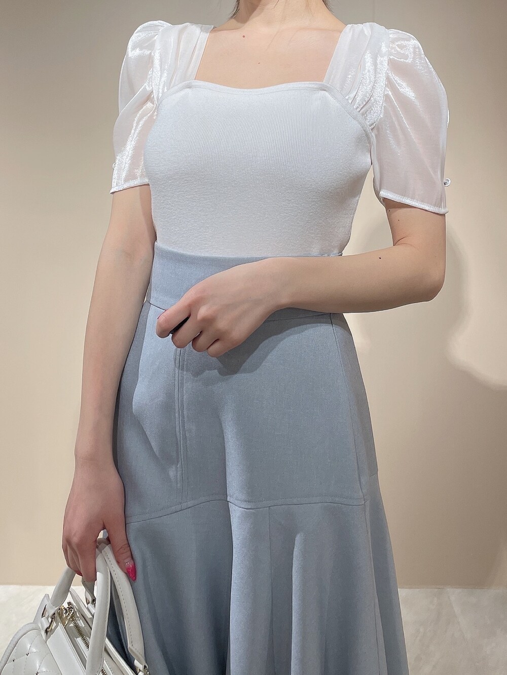 ホワイト系のニット/セーター、ブルー系のスカートを着用したレディースの春コーディネートの6枚目の写真