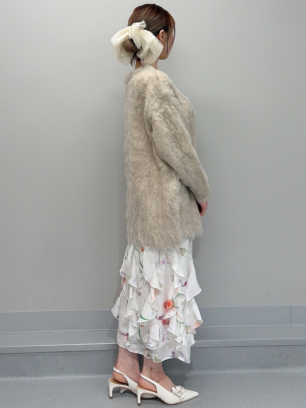 ベージュ系のカーディガン/ボレロ、ホワイト系のワンピース、ホワイト系のパンプスを着用したレディースの冬コーディネートの3枚目の写真