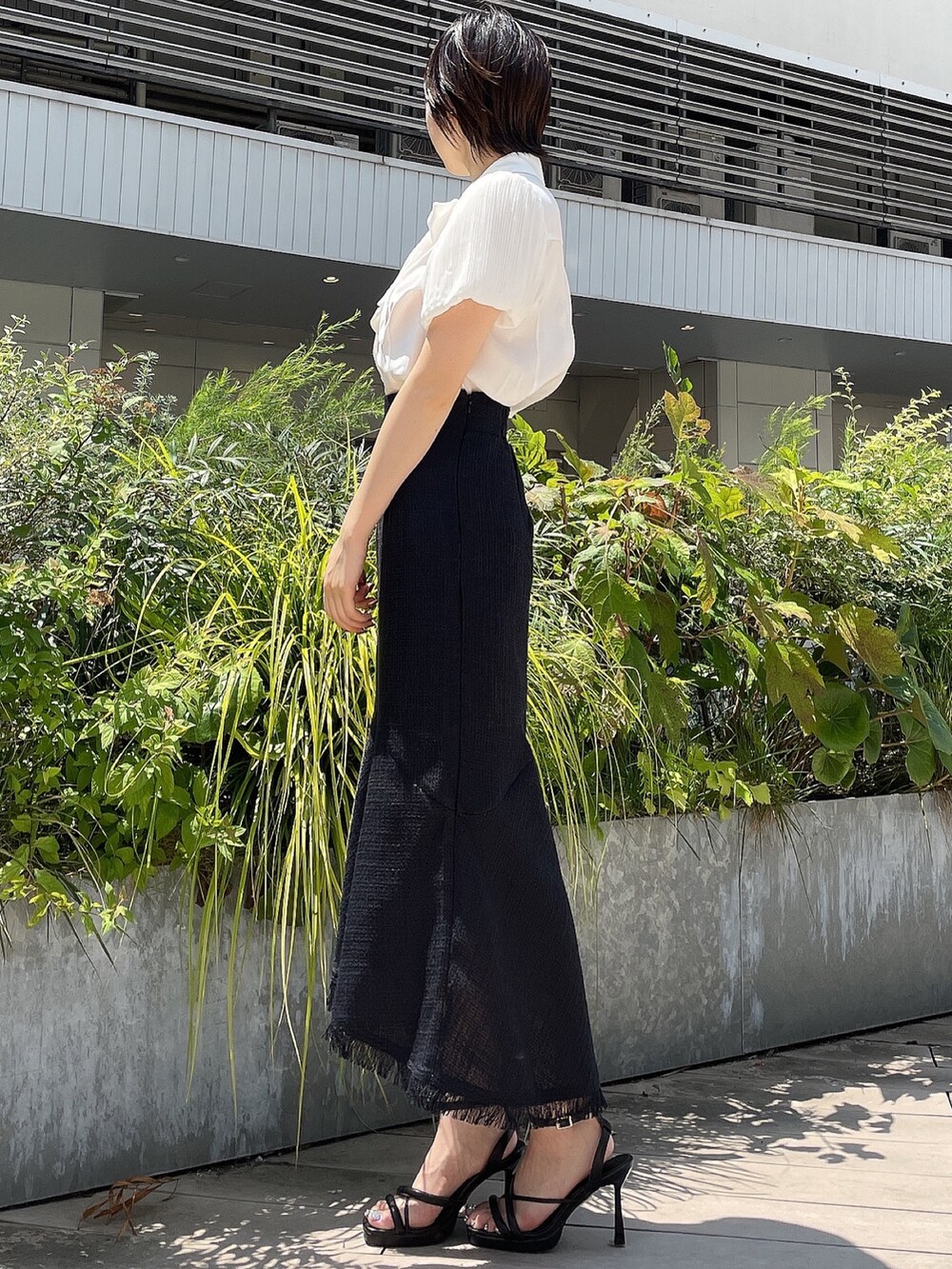 ブラック系のスカート、ホワイト系のシャツ/ブラウス、ブラック系のサンダルを着用したレディースの夏コーディネートの3枚目の写真