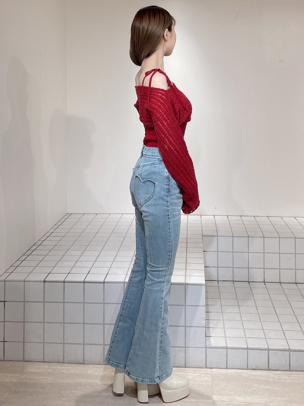 レッド系のニット/セーター、ブルー系のデニムパンツ、ホワイト系のブーツを着用したレディースの冬コーディネートの3枚目の写真