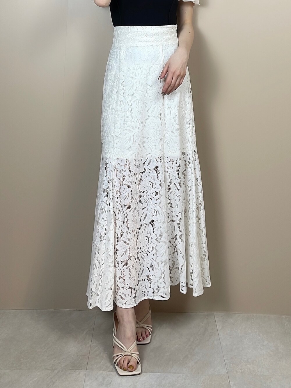 ホワイト系のサンダル、ホワイト系のスカート、ブラック系のニット/セーターを着用したレディースの春コーディネートの7枚目の写真