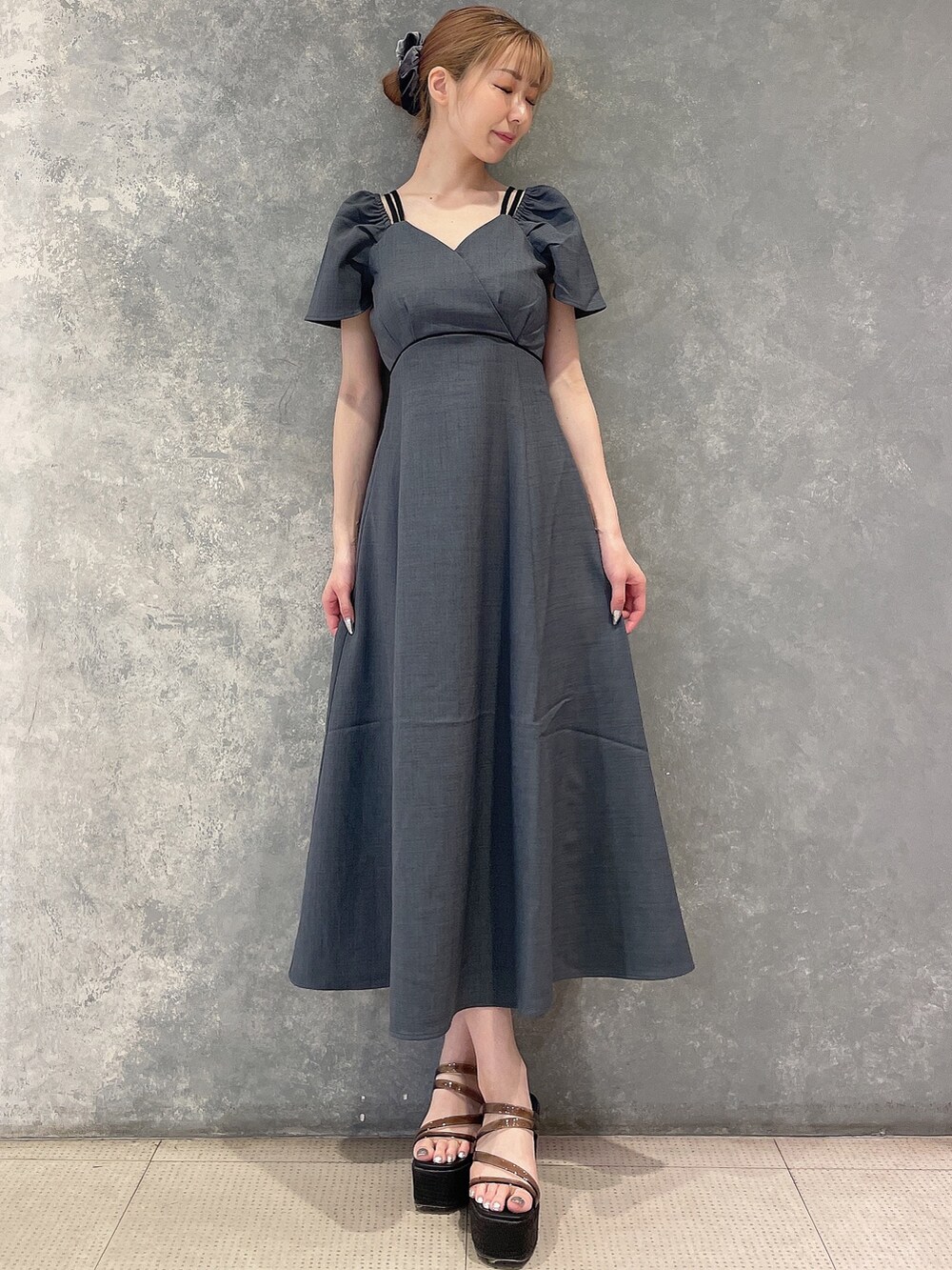 グレー系のワンピース、ブラック系のサンダル、グレー系のシュシュを着用したレディースの夏コーディネートの4枚目の写真