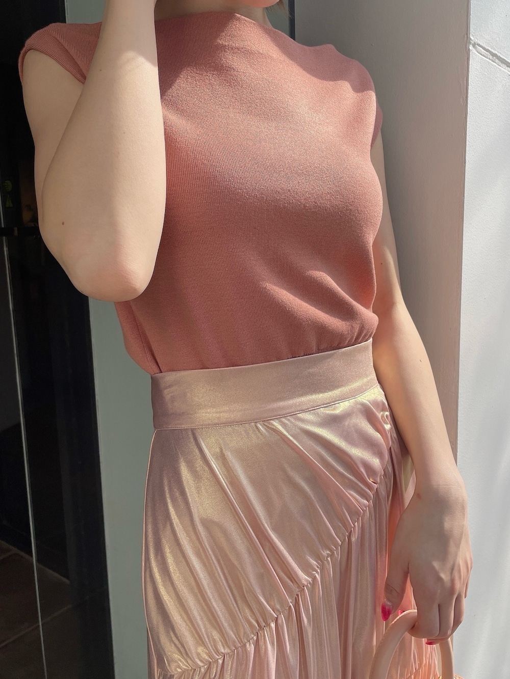 オレンジ系のニット/セーター、ゴールド系のスカート、ピンク系のハンドバッグを着用したレディースの春コーディネートの6枚目の写真