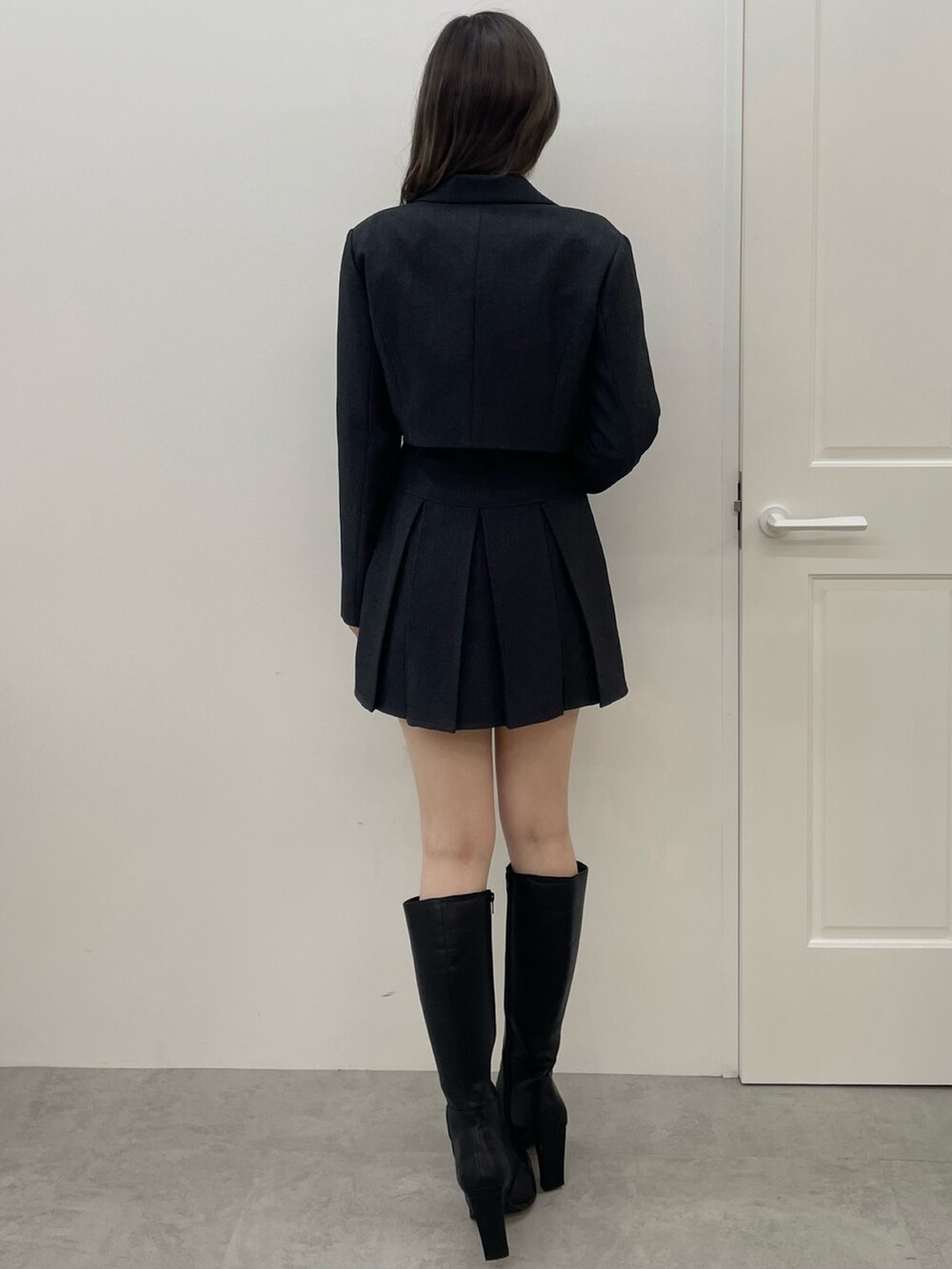 グレー系のテーラードジャケット、グレー系のスカート、ブラック系のブーツを着用したレディースの夏コーディネートの4枚目の写真