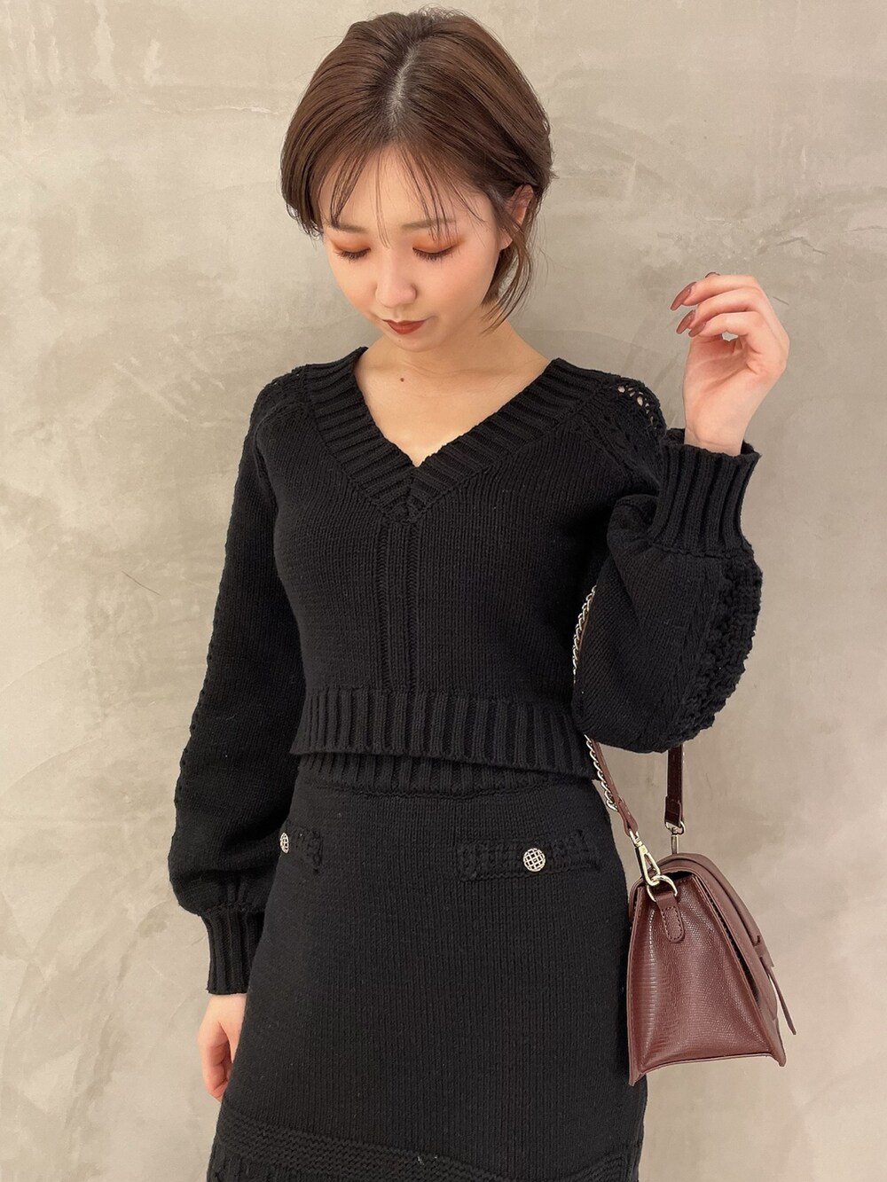 ブラウン系のハンドバッグ、ブラック系のブーツ、ブラック系のニット/セーターを着用したレディースの秋コーディネートの5枚目の写真