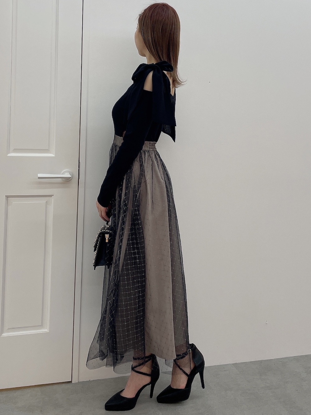 ブラック系のワンピース、ブラック系のハンドバッグ、ブラック系のパンプスを着用したレディースの冬コーディネートの3枚目の写真