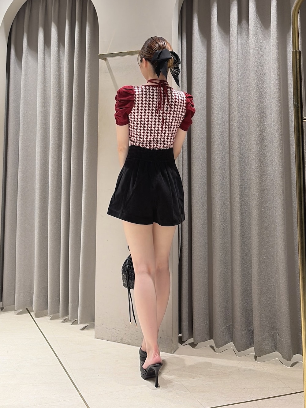 レッド系のニット/セーター、ブラック系のその他パンツ、ブラック系のハンドバッグを着用したレディースの夏コーディネートの3枚目の写真