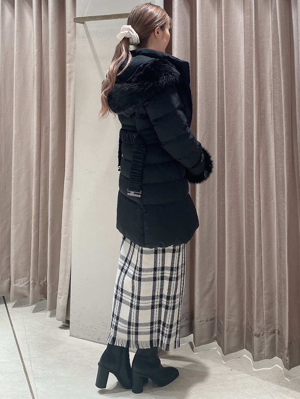 ブラック系のダウンジャケット/コート、グレー系のニット/セーター、ホワイト系のスカートを着用したレディースの秋コーディネートの3枚目の写真