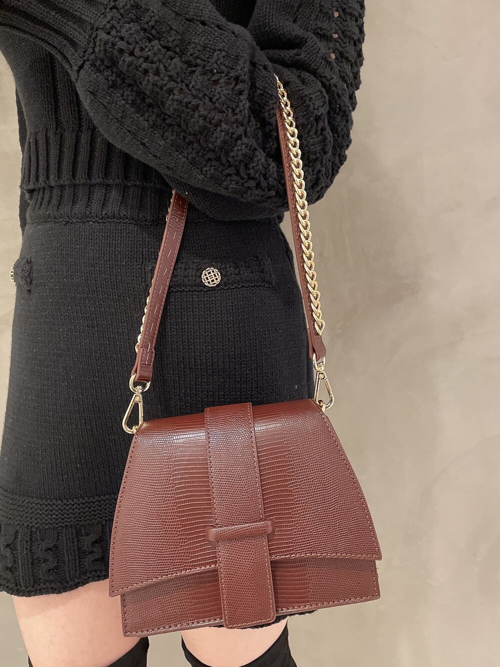 ブラウン系のハンドバッグ、ブラック系のブーツ、ブラック系のニット/セーターを着用したレディースの秋コーディネートの6枚目の写真