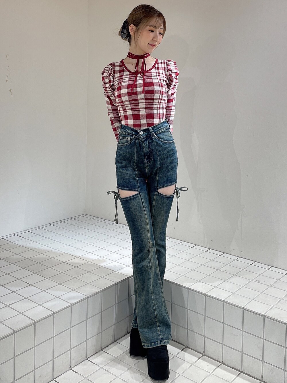 レッド系のニット/セーター、ブルー系のデニムパンツ、ブラック系のブーツを着用したレディースの秋コーディネートの2枚目の写真