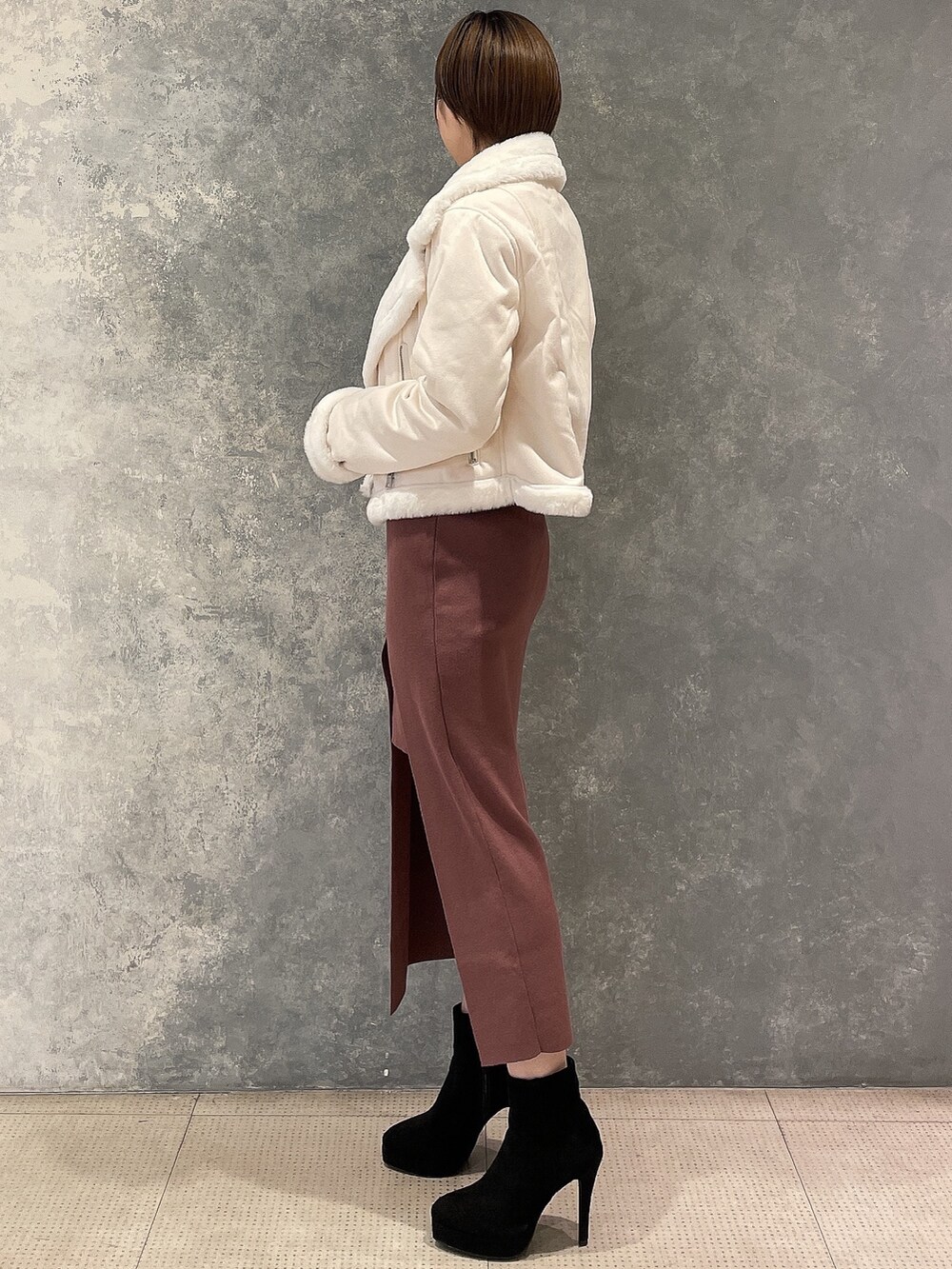 ブラック系のブーツ、ホワイト系のブルゾン、ブラウン系のワンピースを着用したレディースの秋コーディネートの2枚目の写真