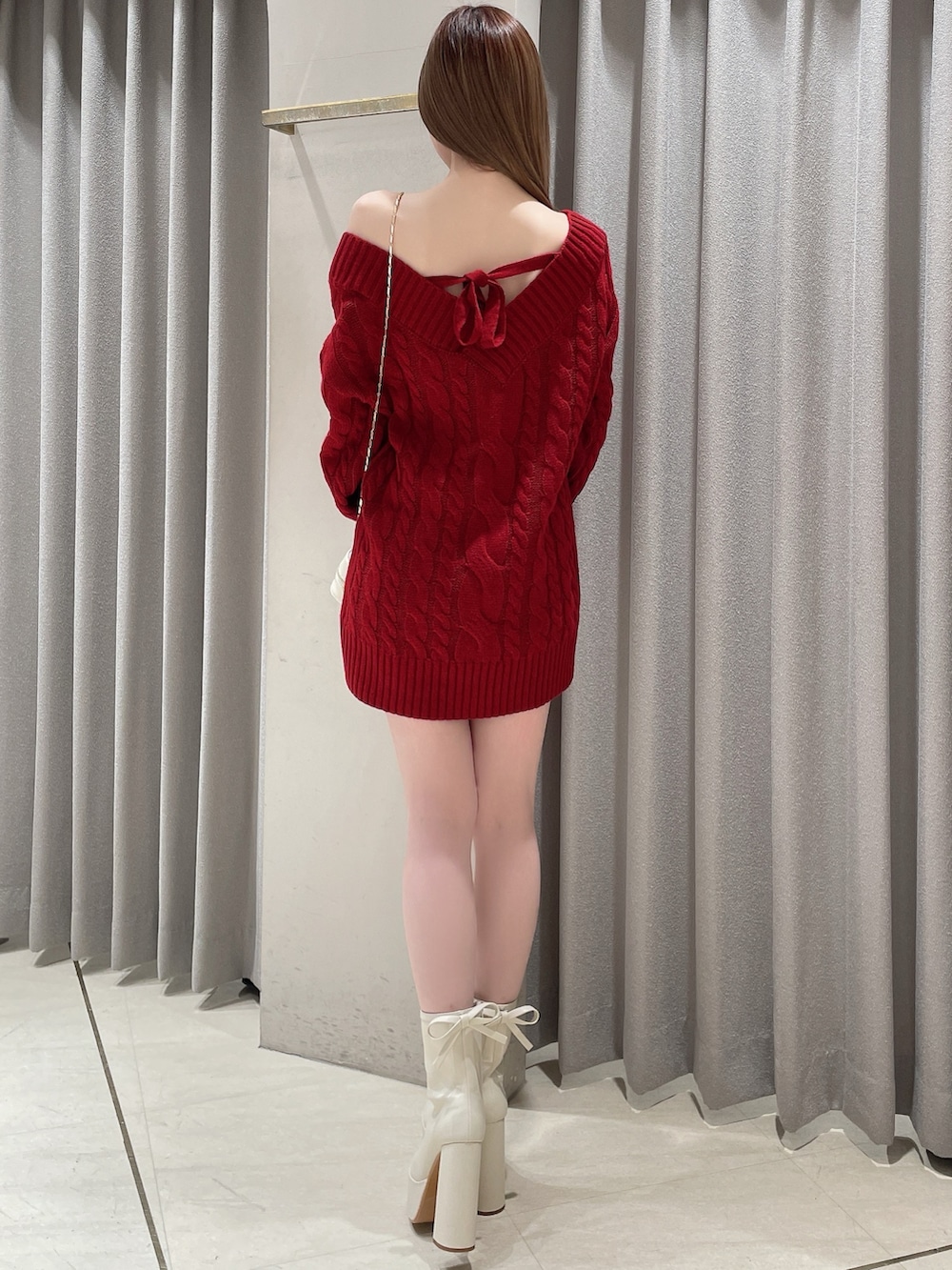 レッド系のニット/セーター、ホワイト系のスカート、ホワイト系のショルダーバッグを着用したレディースの冬コーディネートの4枚目の写真