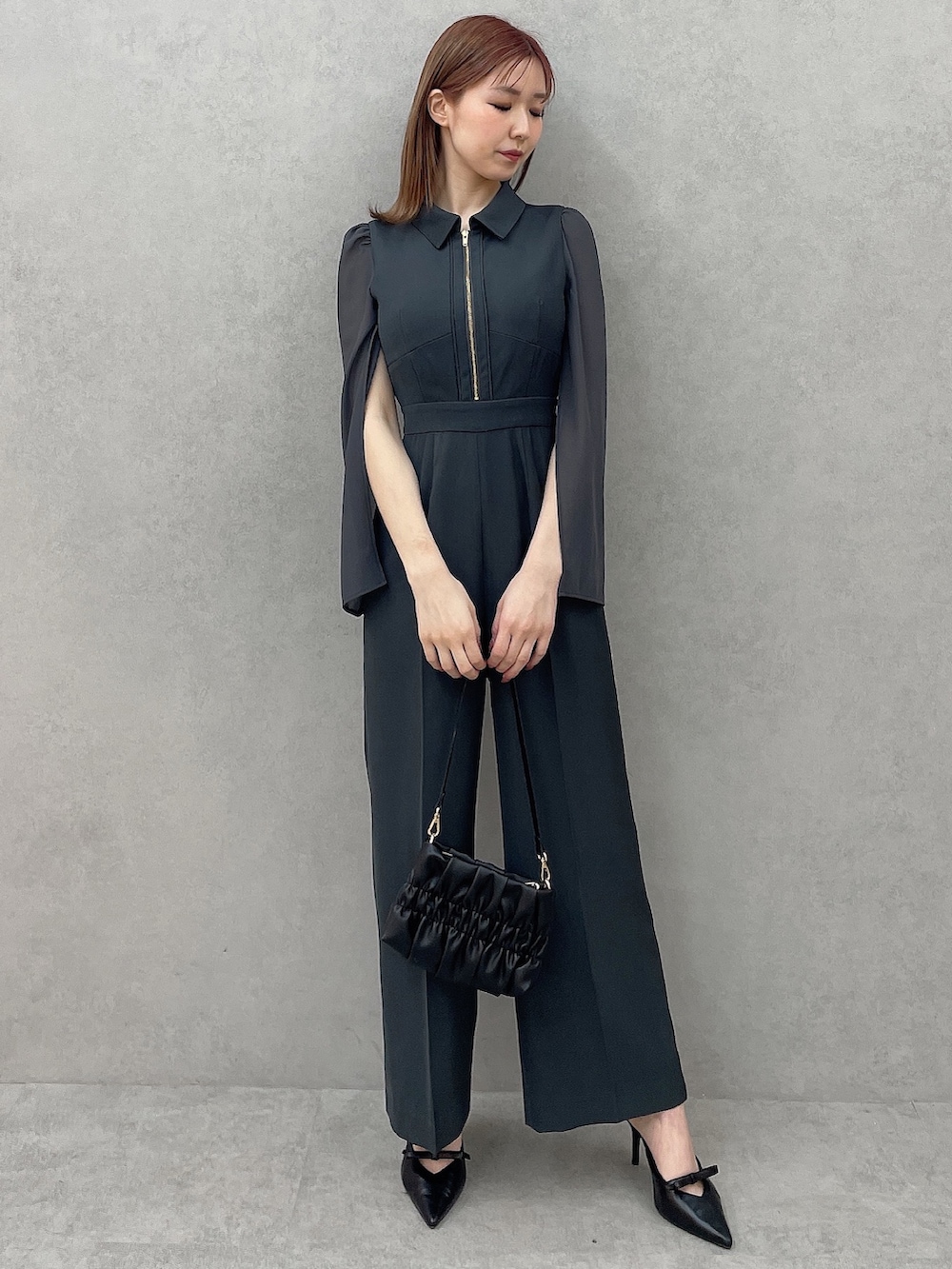 グレー系のつなぎ/オールインワン、ブラック系のハンドバッグ、ブラック系のパンプスを着用したレディースの冬コーディネートの2枚目の写真