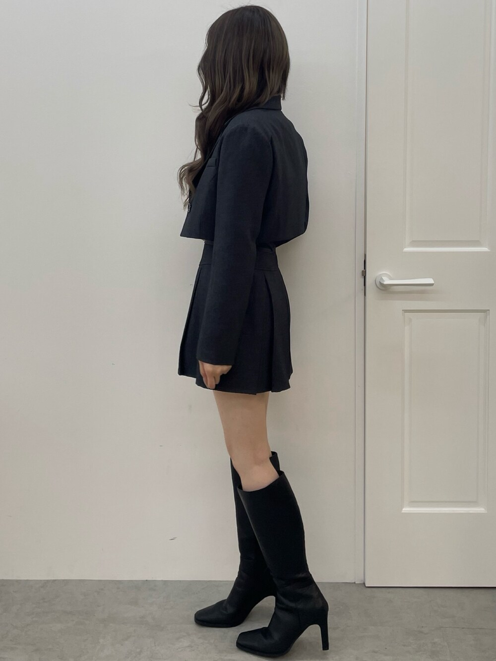 グレー系のテーラードジャケット、グレー系のスカート、ブラック系のブーツを着用したレディースの夏コーディネートの3枚目の写真