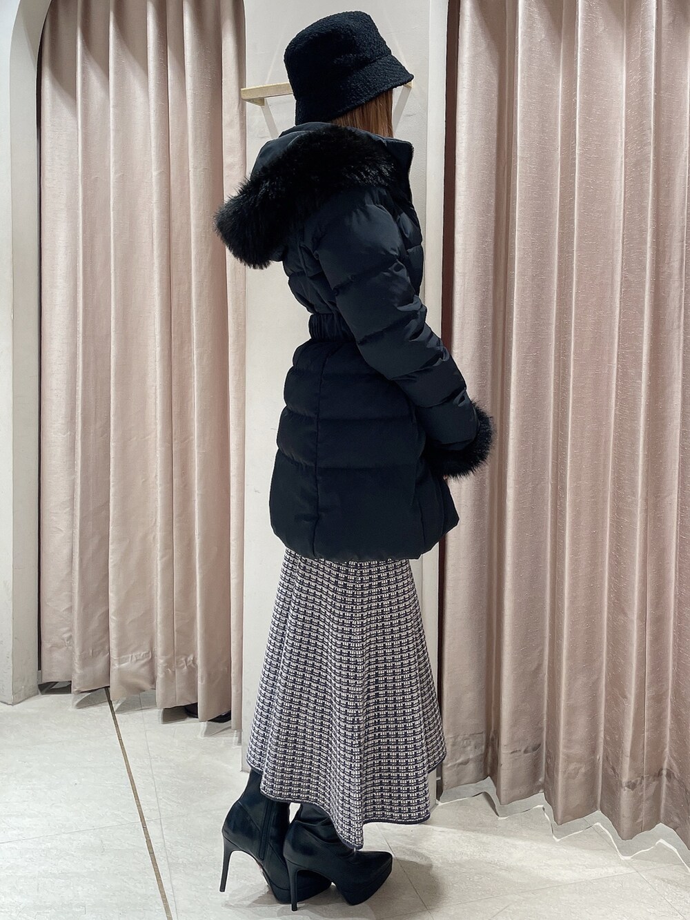 ブラック系のダウンジャケット/コート、ブルー系のワンピース、ブラック系のブーツを着用したレディースの冬コーディネートの2枚目の写真