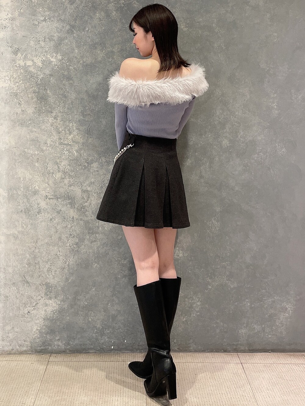 ブルー系のニット/セーター、グレー系のスカート、ブラック系のブーツを着用したレディースの秋コーディネートの3枚目の写真